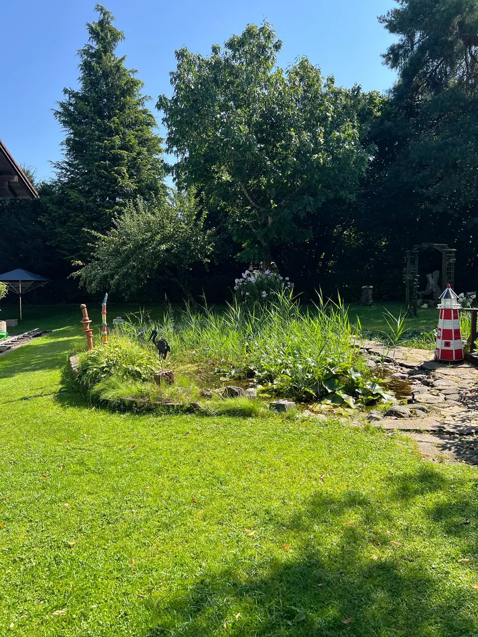 Garten mit Teich und kleinem Leuchtturm
