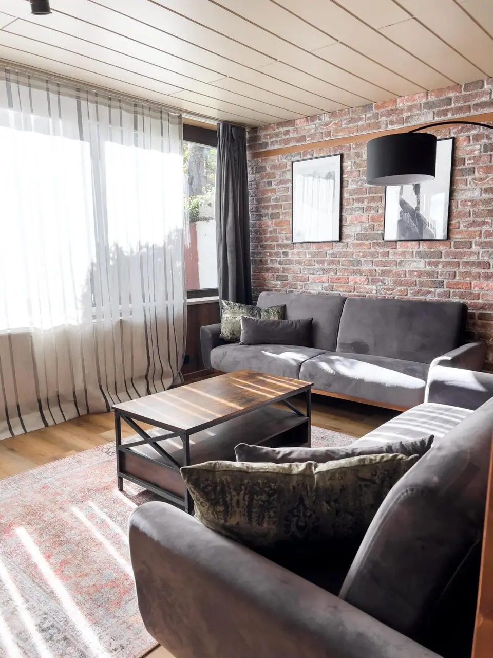 Sonniges Wohnzimmer mit Backsteinwand und großem Fenster